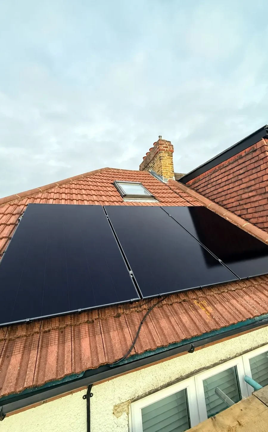All-black solar panels around a roof window on a tiled roof in Romford, fitted by ECONEXIS
