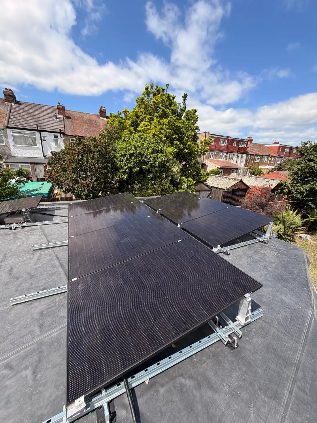 Tilt-frame solar array on a flat roof in Romford with the street beyond