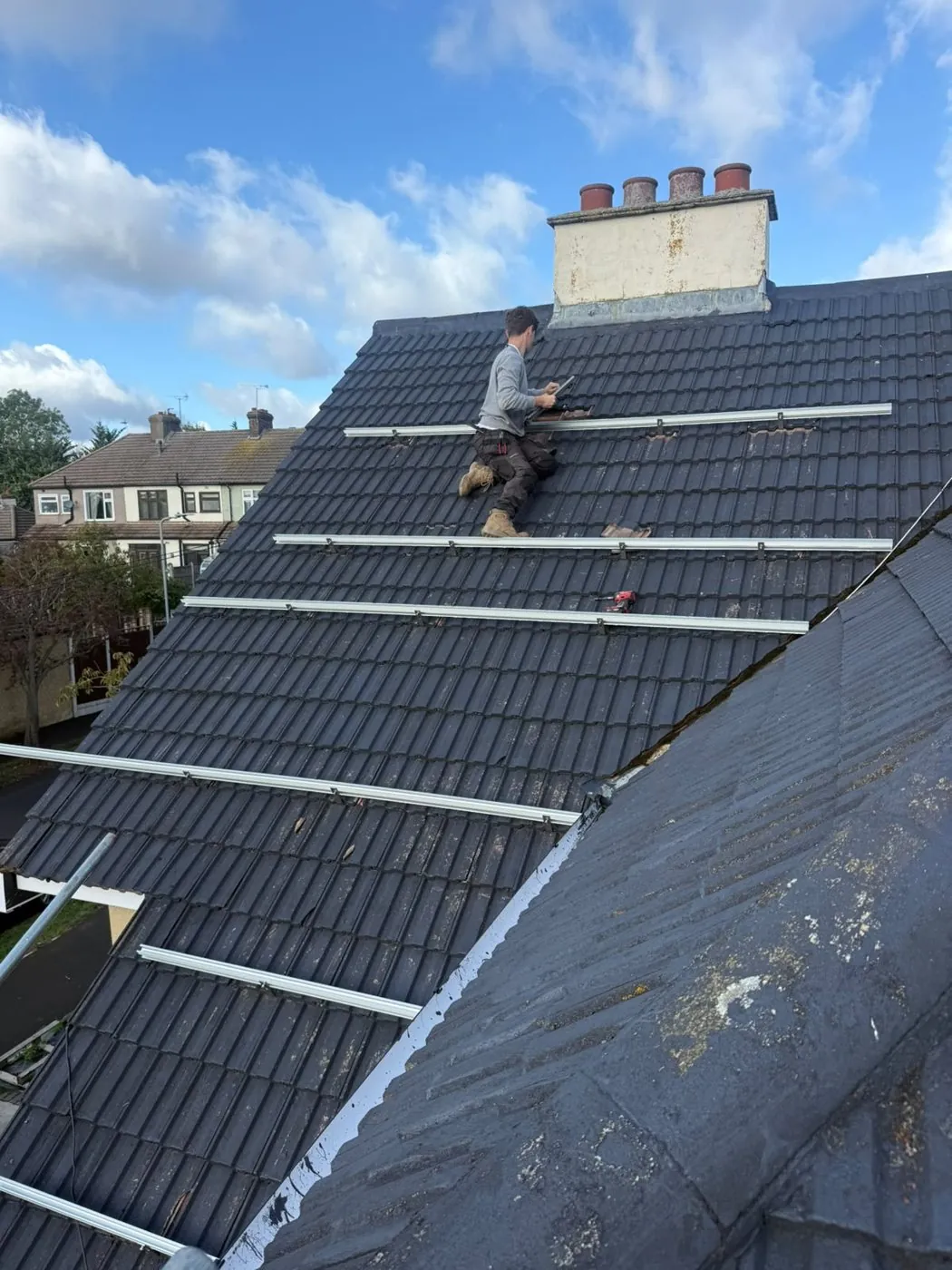 ECONEXIS installers fixing solar rails on the Romford roof from the scaffold